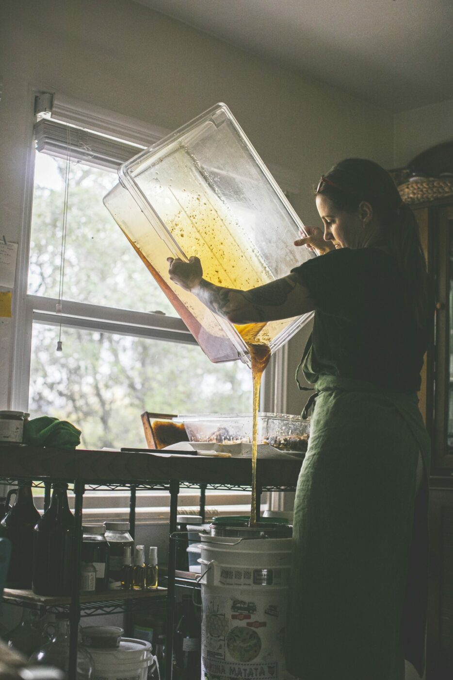 Candice Koseba strains freshly crushed honey before bottling. The honey is unprocessed and unfiltered. (Bryan Meltz/Sonoma Magazine)