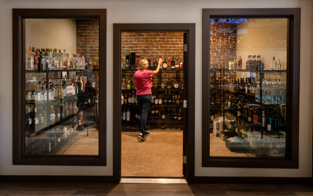 Torches new owner Alice Kilgore finds a bottle or the bar in their locked liquor cabinet just off the bar Tuesday, May 16, 2023. (John Burgess/The Press Democrat)