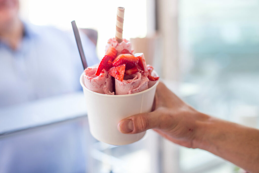 Strawberry ice cream with strawberry topping; Stir-fried ice cream Roll with spoon and chocolate stick. (Shutterstock)