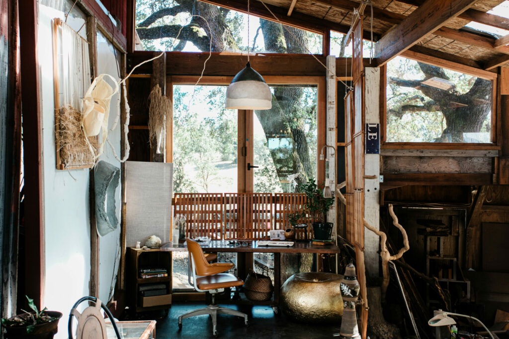 Morgania Moore’s studio in an adjacent outbuilding is a wonder of natural finds from around the Alexander Valley property, including twisted branches, seed pods, and tumbleweeds. She works on jewelry projects at the desk facing the window. (Eileen Roche / Sonoma Magazine)