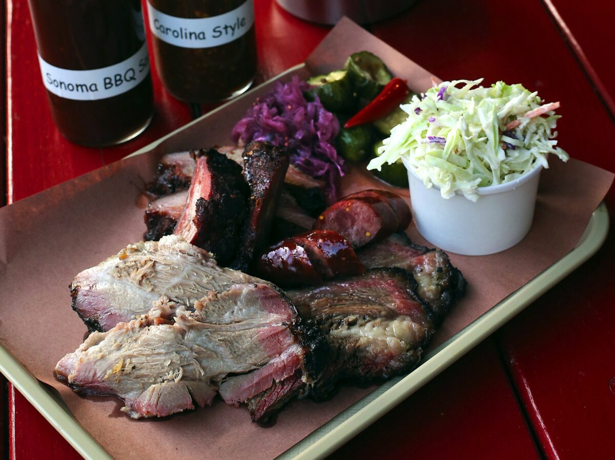 Customers order baby back ribs, sausage, pork shoulder, short ribs and beef brisket by the pound to create their mixed platter at the Cochon Volant BBQ Smoke House in Sonoma. (John Burgess / The Press Democrat)