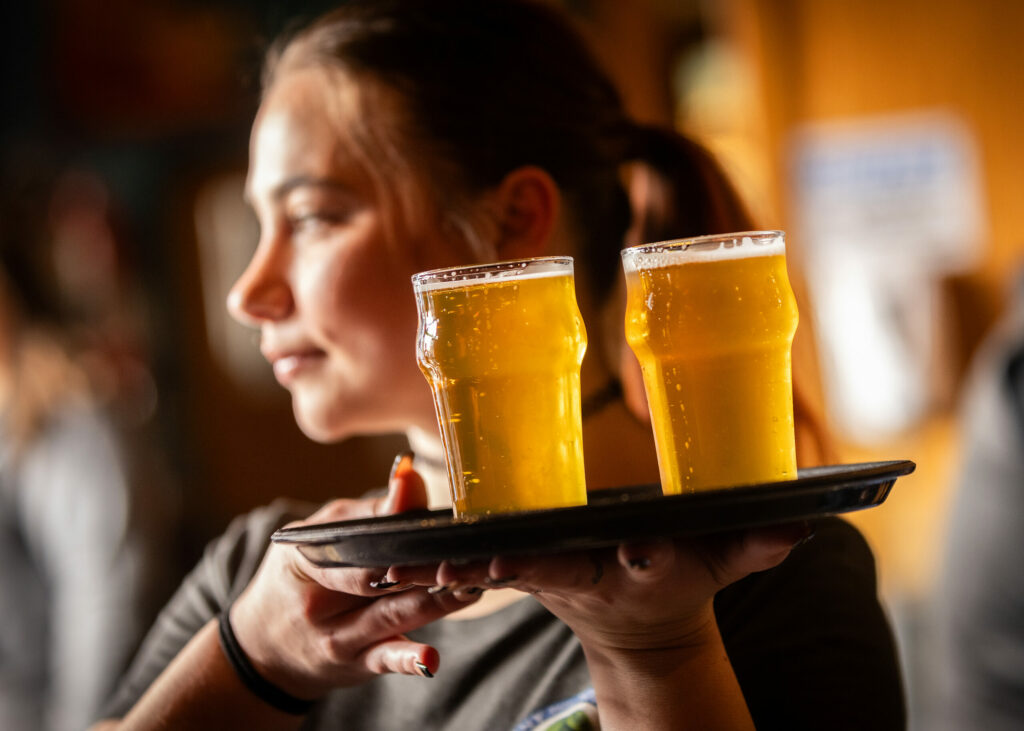 Server Cerra Modar carries a tray of Russian River Brewing Co. 20th anniversary Pliny the Younger triple IPA for guest on the first day of the limited release at the brewpub in Santa Rosa, Friday, March 22, 2024. (John Burgess / The Press Democrat)