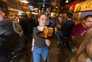 Server Cerra Modar carries a tray of Russian River Brewing Co. 20th anniversary Pliny the Younger triple IPA for guest on the first day of the limited release at the brewpub in Santa Rosa, Friday, March 22, 2024. (John Burgess / The Press Democrat)