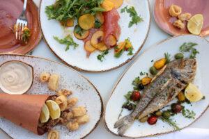 From left, fried Rhode Island calamari, tuna carpaccio with nectarine and arugula, and the whole-roasted orata fish at Scala Osteria in Napa, Wednesday, September 6, 2023. (Beth Schlanker / The Press Democrat)