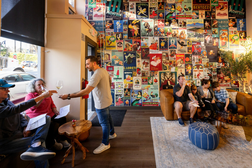 L'Oro di Napoli co-owner passes out glasses of champagne for guest waiting in the lobby Friday, February 28, 2025, in Petaluma. (John Burgess / The Press Democrat)