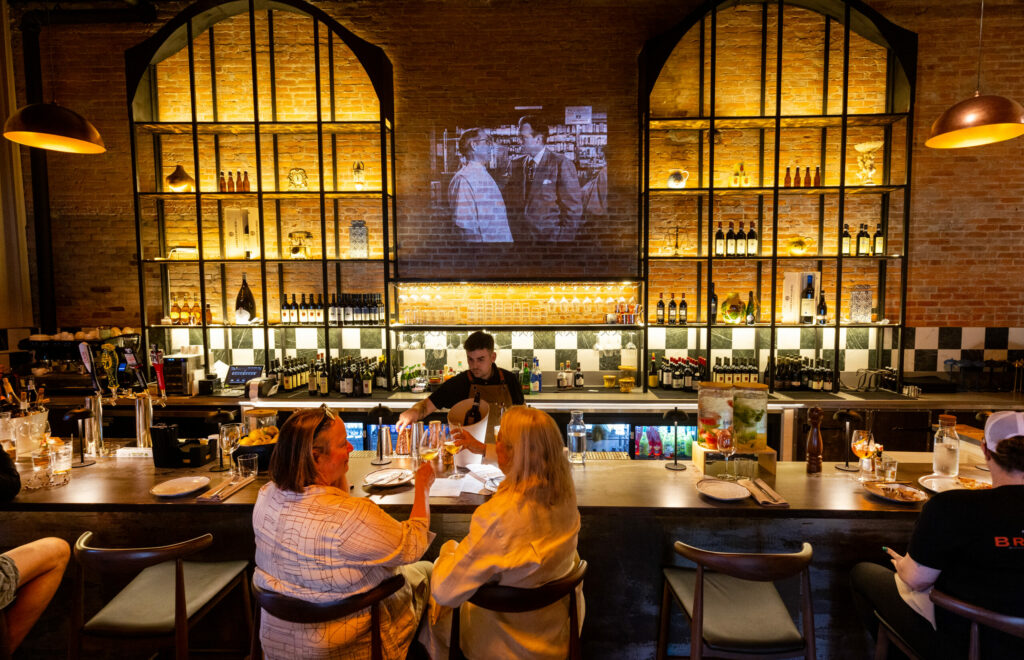 The bar with old movies shown on the brick wall at the new second location for L'Oro di Napoli Friday, February 28, 2025, in Petaluma. (John Burgess / The Press Democrat)