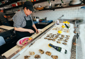 Mary Cecile Agneberg, the “MotherShucker,” brings a short knife and plenty of muscle when prying open mollusks at Trillium Winebar & Taproom Friday, February 28, 2025, on Main Street in Guerneville. (John Burgess / The Press Democrat)