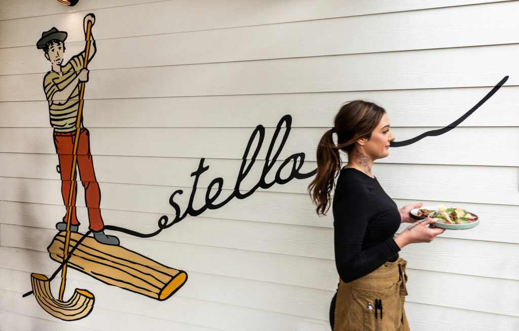 Dominique Watts carries a salad to the covered porch dining area at Stella Wednesday, March 26, 2025, in Kenwood. (John Burgess / The Press Democrat)