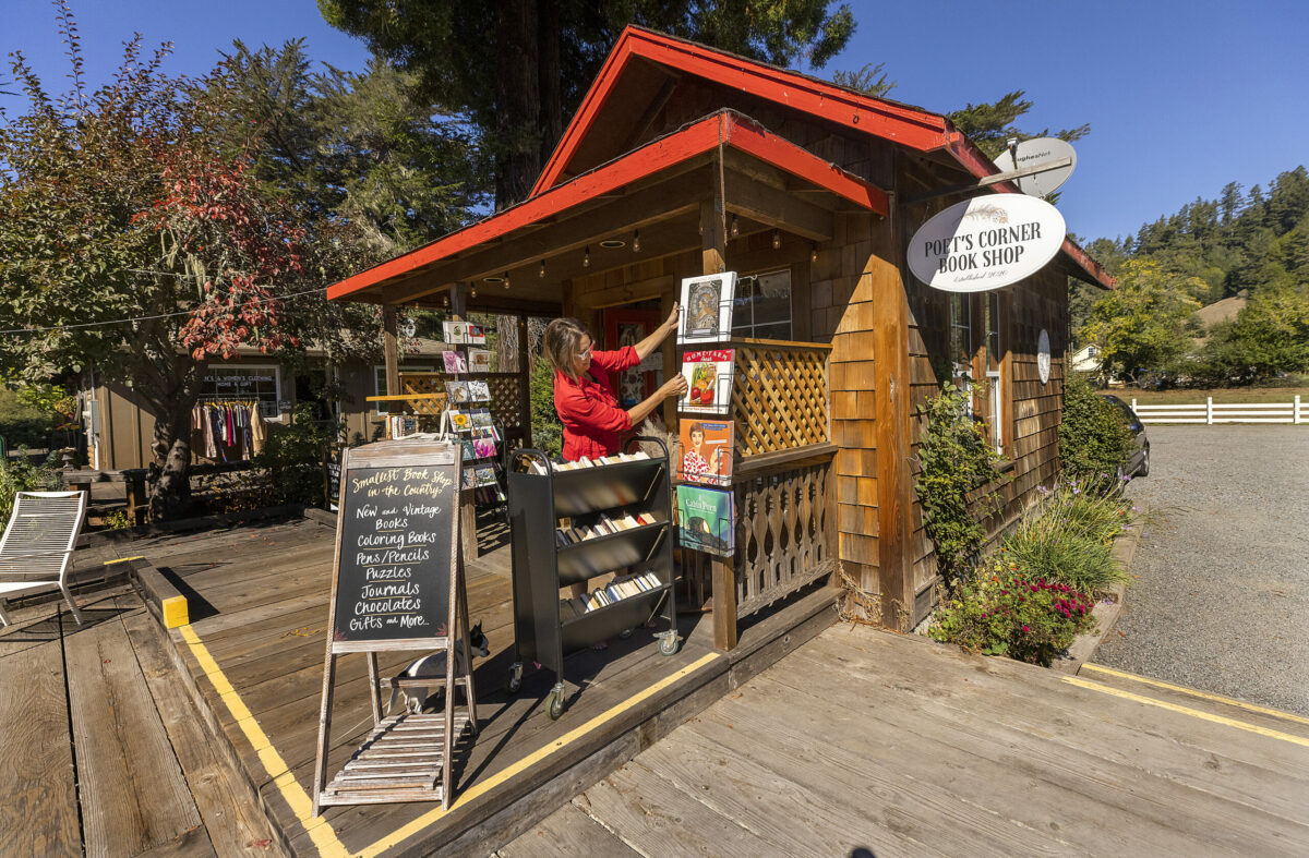 Stephanie Culen, owner of Poet's Corner Book Shop, "decorates" the outside of her tiny, 275-square-foot shop, before opening in Duncans Mills on Thursday, September 30, 2021. (John Burgess/The Press Democrat)
