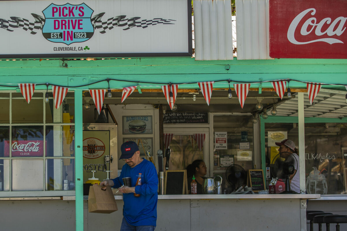 A guest at Pick's Drive-In carries his meal and drinks back to his truck in downtown Cloverdale Tuesday June 14, 2022 (Chad Surmick / Press Democrat)