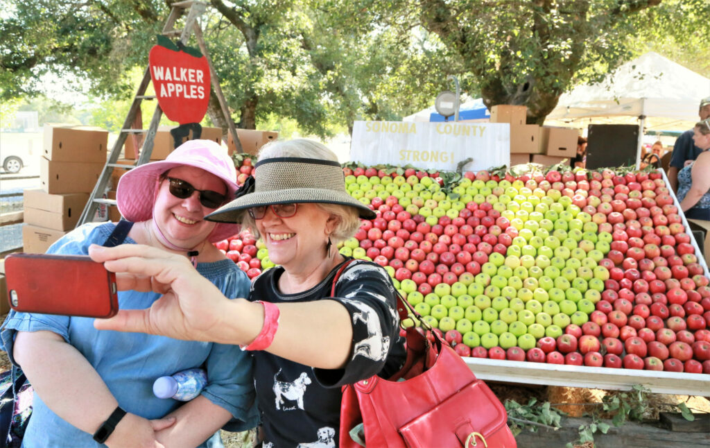 Volunteers, from San Jose, Marie Taylor Harper (left) and Mary Ann May-Pumphrey snap a 'selfie' at the 45th Gravenstein Apple Fair at Ragle Ranch Park in Sebastopol. (Will Bucquoy/For The Press Democrat)