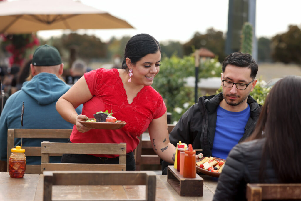 La Cheve Bakery and Brews owner Cinthya Cisneros delivers food to a table in Napa Sunday, Nov. 17, 2024. (Beth Schlanker / The Press Democrat)