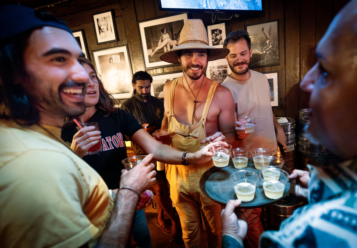 Auctioneer Nick Schwanz, center in hat, and his friends grab Champagne to celebrate raising more than $1 million for local charities over the past 20 years on Give Back Tuesdays, June 24, 2025, at the Rainbow Cattle Co. in Guerneville. (John Burgess / The Press Democrat)