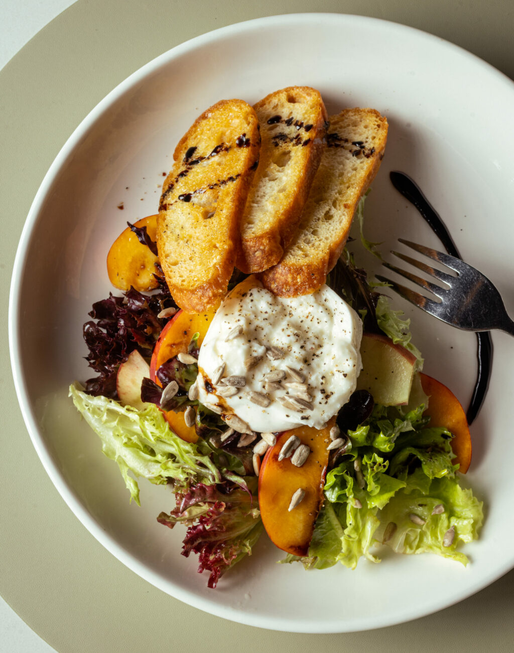 Peaches and Burrata with mixed greens, sunflower seeds and balsamic gastrique from The Burrow Wednesday, July 9, 2025 just off the square in Healdsburg. (John Burgess / The Press Democrat)
