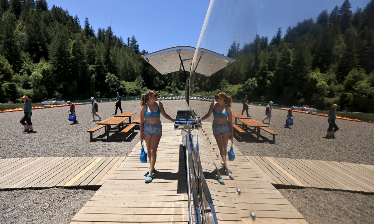 Reflected in the new Johnson's Beach snack bar on the Russian River in Guerneville, Ona Schiller from Tulsa, Oklahoma waits for her food order on the first day of calendar summer, Wednesday, June 21, 2023. (Kent Porter / The Press Democrat)