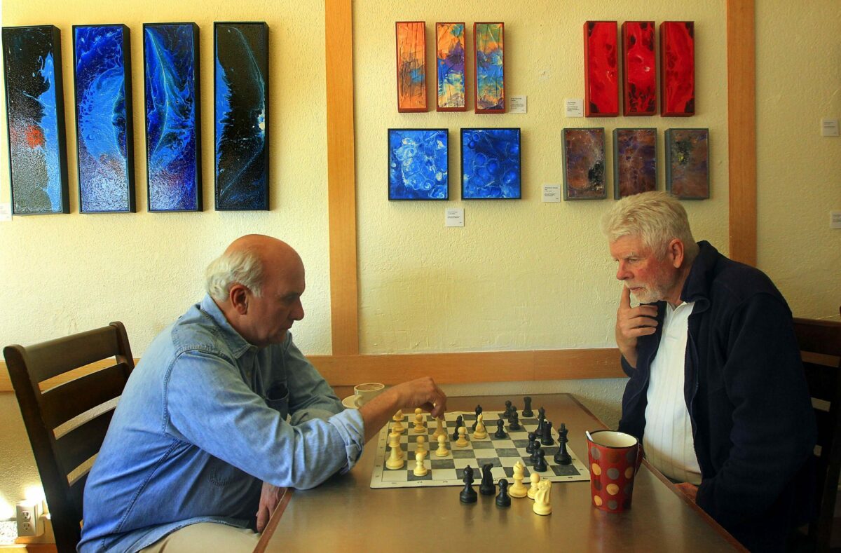 Poet and chess player Ed Coletti makes a move as retired electrical contractor Bruce Wishard looks on while playing a match at SoCo Coffee in Santa Rosa. (John Burgess / The Press Democrat, file)