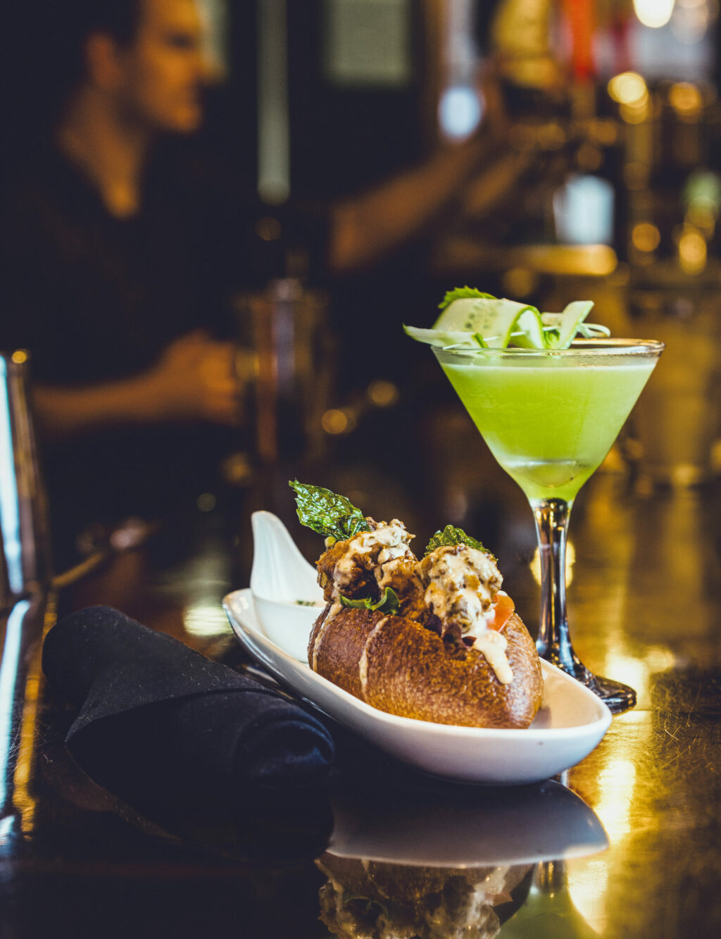Oyster Po’ Boy with fried Drakes Bay oysters, lettuce, pickles, tomatoes and remoulade with a Flapper’s Delight cocktail from the Grove Speakeasy Thursday, Oct. 9, 2025 in Penngrove. (John Burgess / The Press Democrat)