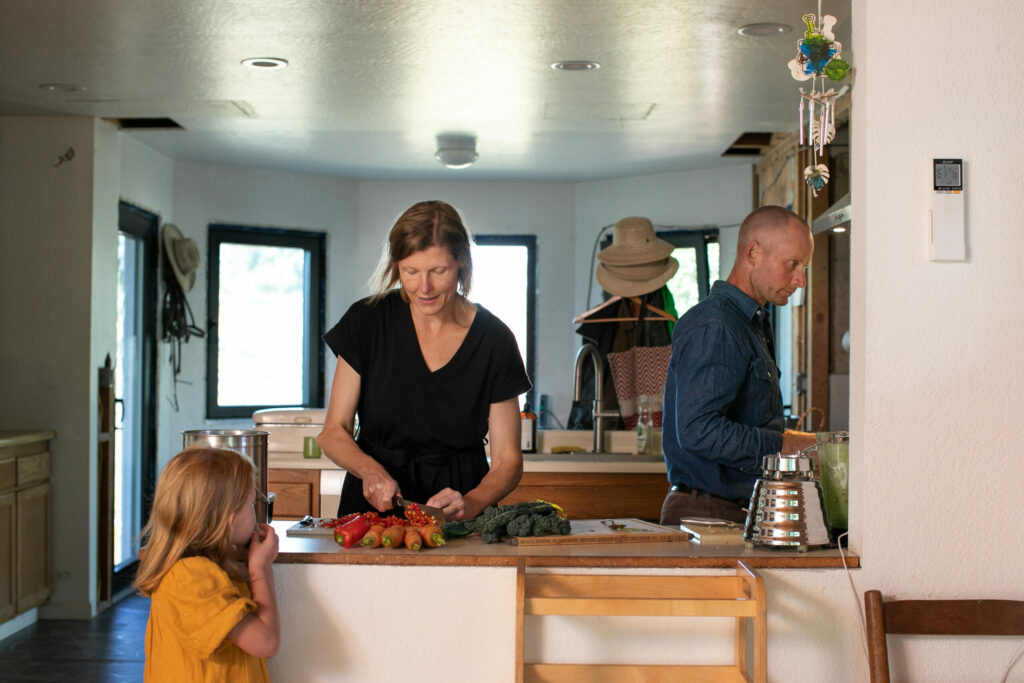 Kristin and Jason Nichols prepare food in their energy efficient kitchen while daughter, Eve, 5, watches. Using an induction cooktop and composting are just a couple of ways the family lessens their carbon footprint. (Eileen Roche / for Sonoma Magazine)