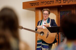 Rabbi Jeremy Morrison stands with his guitar in front of his congregation during Shabbat at Congregation Shomrei Torah on August 15, 2025. (Abraham Fuentes/For The Press Democrat)