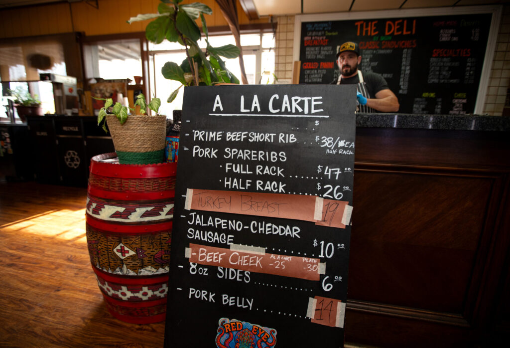 Bob Costarella, owner and pitmaster, works preparing meats behind the counter where his sign is displayed at his “Red Eye Barbecue” pop up, held on Saturdays at Sazon Peruvian Cuisine & Deli on November 15, 2025. (Darryl Bush / For The Press Democrat)