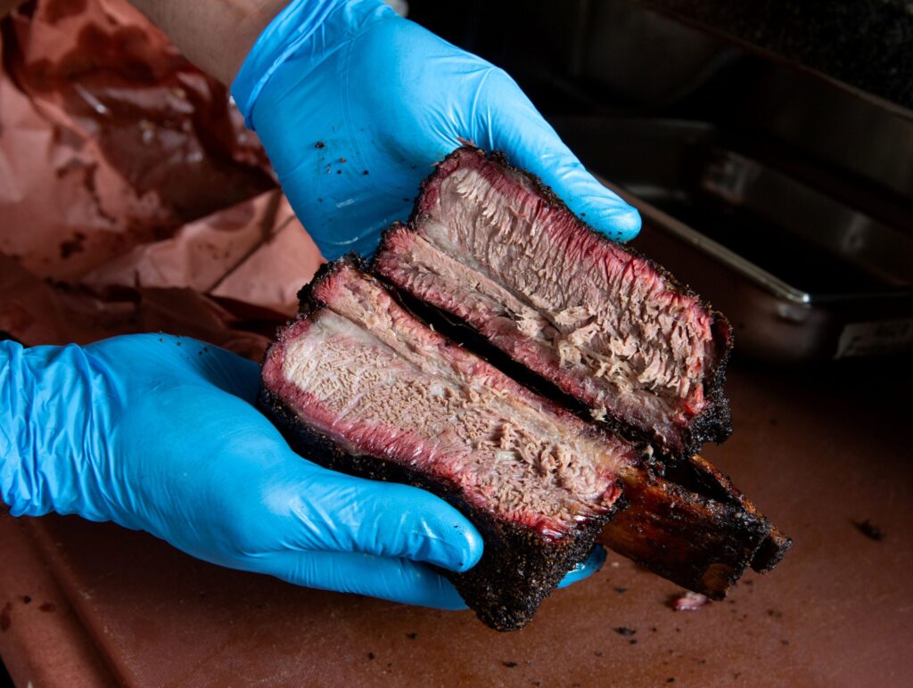 Bob Costarella, owner and pitmaster, holds barbecued beef ribs at his “Red Eye Barbecue” pop up, held on Saturdays at Sazon Peruvian Cuisine & Deli on Nov. 15, 2025. (Darryl Bush / For The Press Democrat)