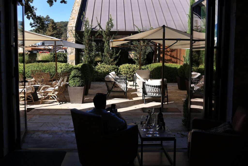 Large, sliding hurricane doors open up to Stewart Cellars tasting patio, Friday, October 21, 2025, in Yountville as Alex Grisanti from Mississippi, relaxes. (Kent Porter / The Press Democrat)