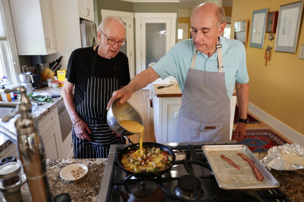 Steve Garner, right, and John Ash make “crustless” frittata with bacon, potatoes and walnuts, in Santa Rosa on Wednesday, July 3, 2024. Ash and Garner co-hosted the KSRO “The Good Food Hour” radio show for nearly 40 years. Ash died Thursday, Aug. 7, 2025, at age 83. (Christopher Chung / The Press Democrat)