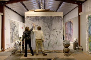 With their wrists bound together, artists Pamela Holmes and Winston Gourley draw with handmade charcoal on a canvas at Stranger Worth studio in Cazadero Thursday, Nov. 20, 2025. (Beth Schlanker / The Press Democrat)