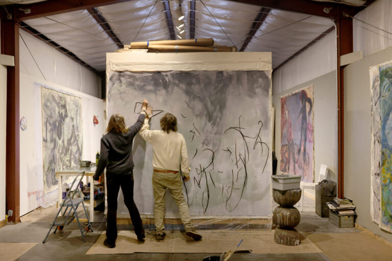 With their wrists bound together, artists Pamela Holmes and Winston Gourley draw with handmade charcoal on a canvas at Stranger Worth studio in Cazadero Thursday, Nov. 20, 2025. (Beth Schlanker / The Press Democrat)
