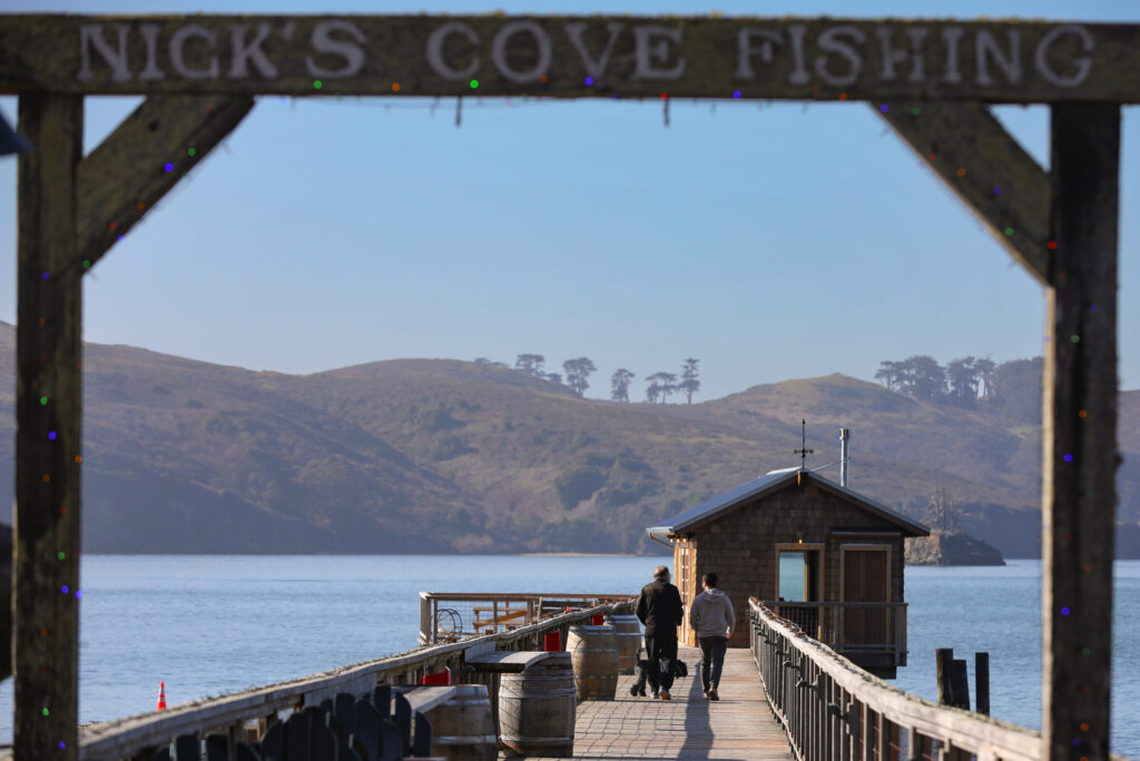 Daniel, left, and son Samuel Green walk Gazpacho on the pier at Nick’s Cove to view the newly reopened Boat Shack in Marshall on Wednesday, December 10, 2025. (Christopher Chung/The Press Democrat)