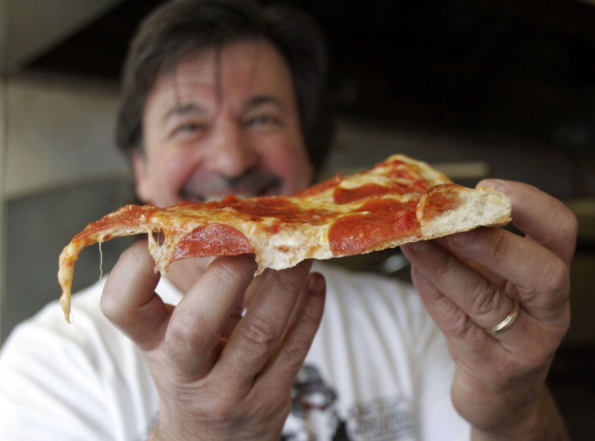 The late Fred Poulos, Mombo's original owner, holding a slice of pepperoni pizza in 2009. The Mombo’s Pizza founder died in June 2020. (The Press Democrat, file)