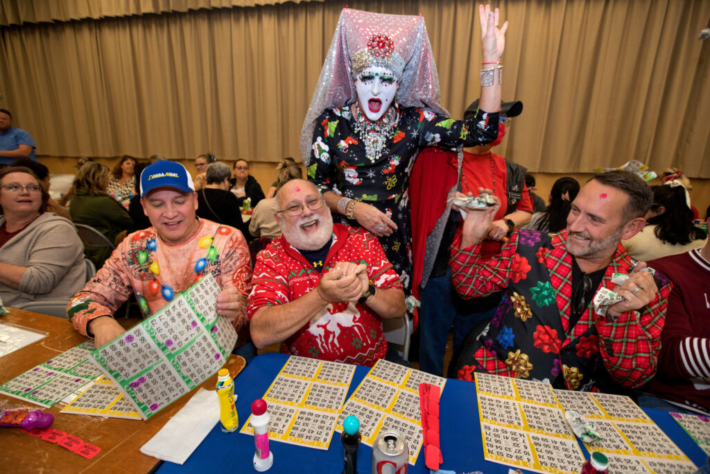 Sister Tooty Too Too Sweet celebrates with bingo winner, DT Passantino, center, with friends Ray DeLeon, left (wearing hat), and Jay Boot, right, all of Guerneville, during the Russian River Sisters of Perpetual Indulgence's Frozen Bingo benefit at the Veterans Memorial Building, Saturday, December 17, 2022, in Santa Rosa. (Darryl Bush/For The Press Democrat)