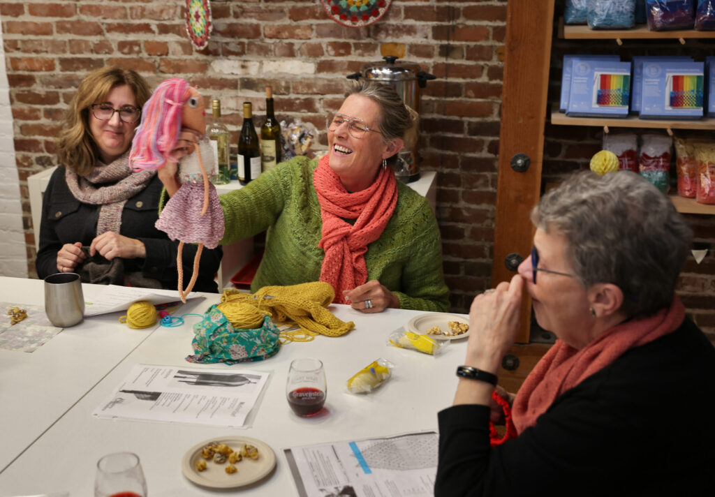 Michele Kesner, center shows a doll she made for her daughter years ago to Cheri Whiting, left, and Andi Safran during a Thursday Knit Night at Castaway Yarn in Santa Rosa on Thursday, November 20, 2025. (Christopher Chung/The Press Democrat)