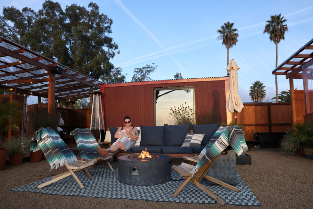 Khephra Molloy reads a book by the fire at Sundrop Sauna in Petaluma Sunday, Nov. 30, 2025. (Beth Schlanker / The Press Democrat)