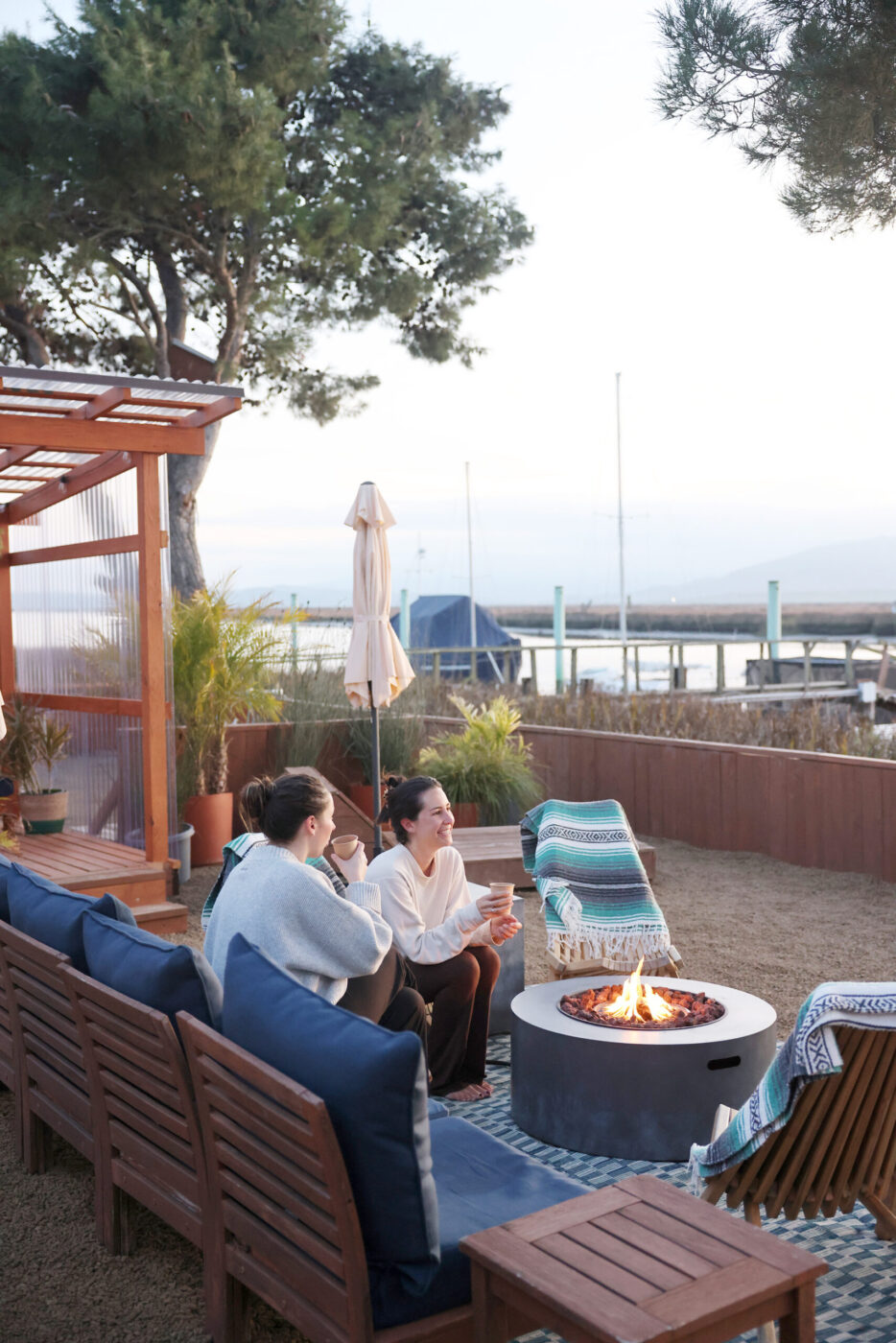 Friends Lucia Mora, right, and Renee Rodgers relax by the fire at Sundrop Sauna in Petaluma Sunday, Nov. 30, 2025. (Beth Schlanker / The Press Democrat)