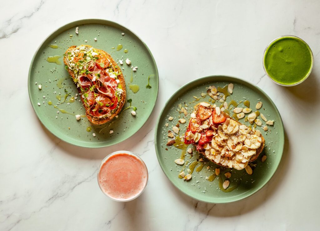 From left, avocado toast topped with prosciutto and sprouts, and the Sweet Crunch toast with almond butter, bananas, strawberries, coconut and almonds from Succo Cold-Pressed in Santa Rosa. (John Burgess / The Press Democrat)