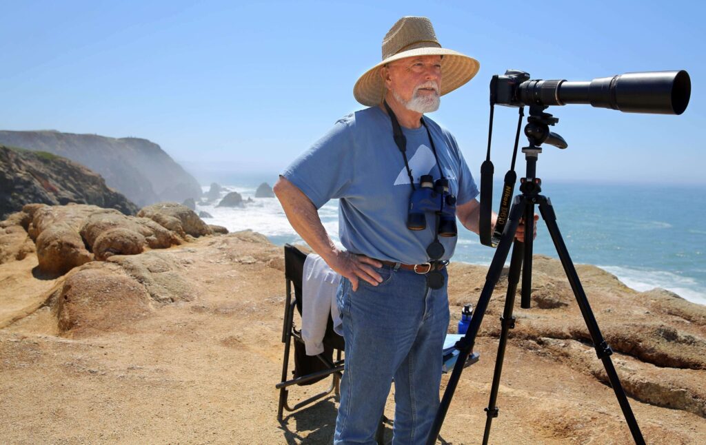 The late Larry Tiller tracks a gray whale and her calf as they migrate north past Bodega Head on Thursday, April 30, 2015. (Christopher Chung / The Press Democrat, file)