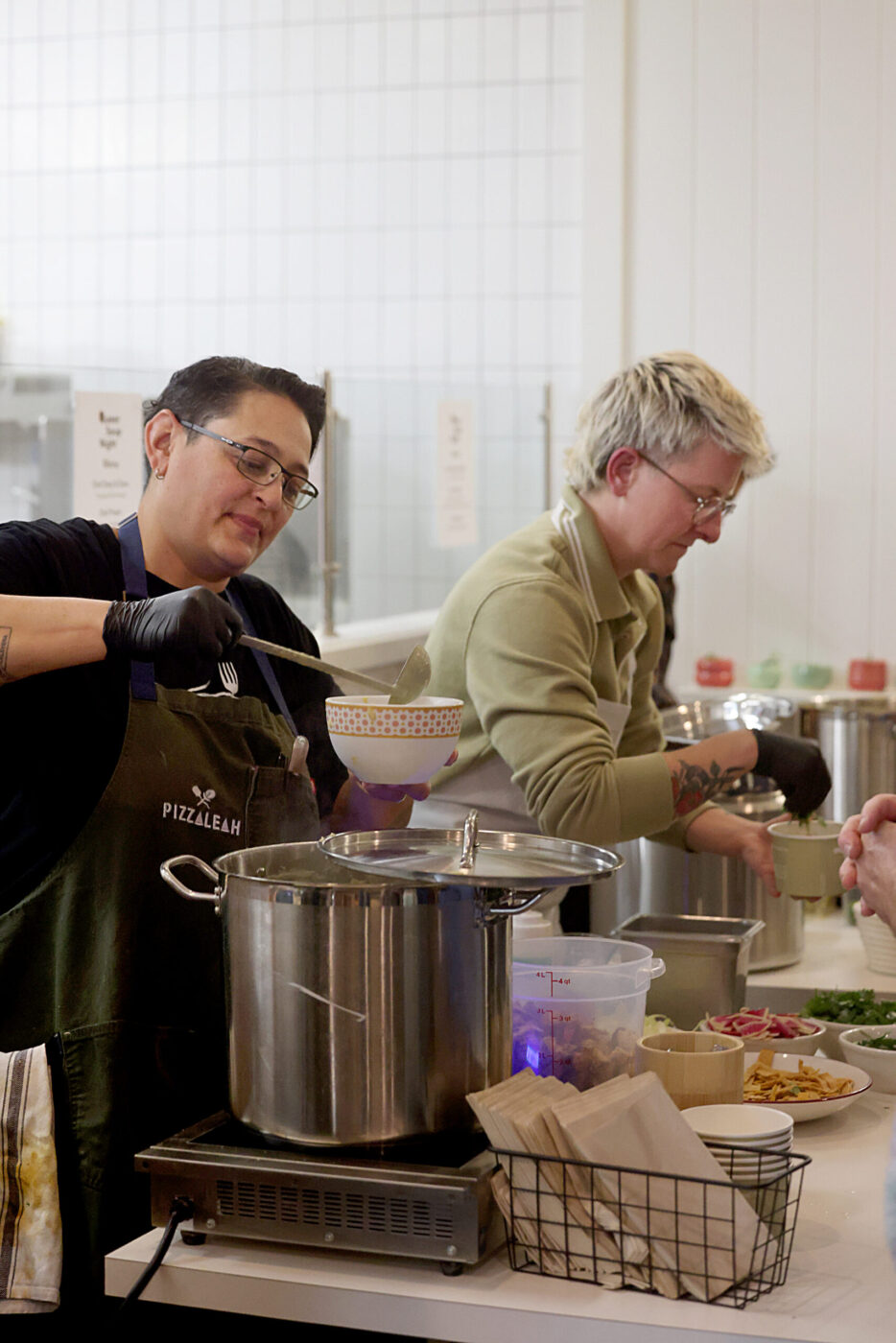 Chefs Leah Scurto, left, and Dany Cleland, right, serve soup during the Queer Soup Night event at Slow Co. Pizza in Cotati Sunday, Nov. 23, 2025. (Beth Schlanker / The Press Democrat)