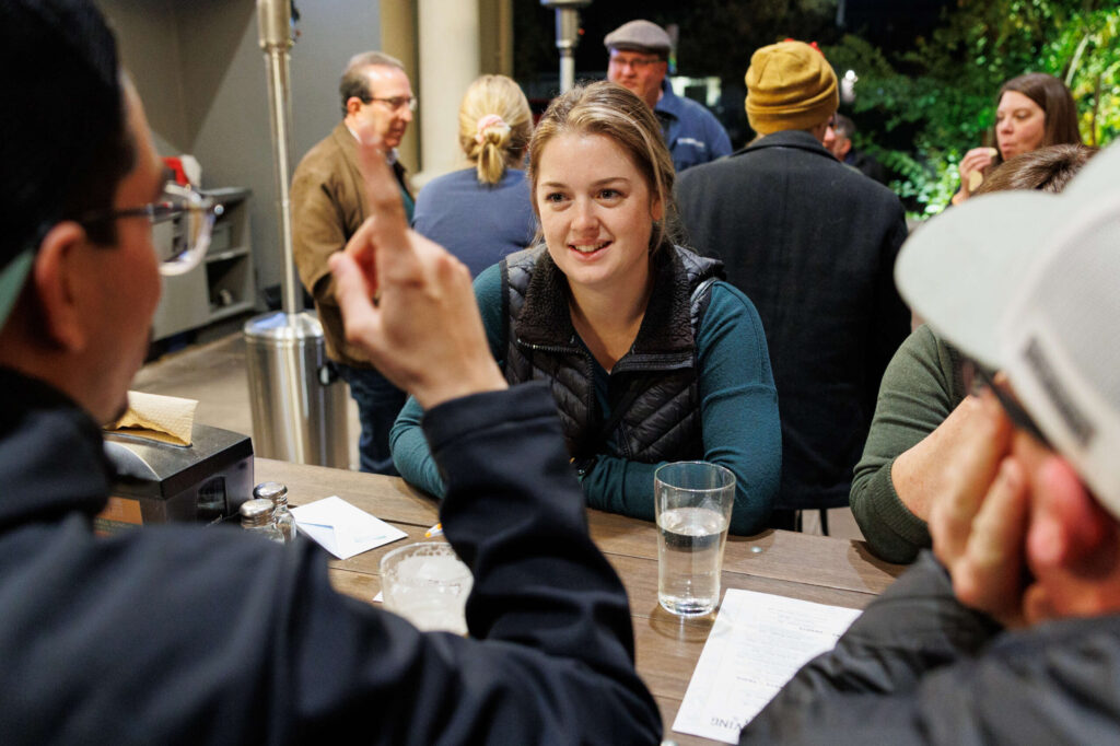 Katie Karns talks to her teammates about the correct answers for the Redwood Empire Food Bank’s Trivia Night at Barrel Brothers Brewing Kitchen & Cocktails in Windsor on Thursday, Dec. 14, 2023. (Abraham Fuentes / For The Press Democrat)