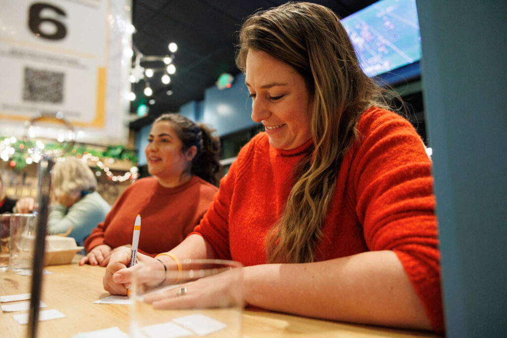 Ashley Babin writes down their answers for the Redwood Empire Food Bank’s Trivia Night at Barrel Brothers Brewing Kitchen & Cocktails in Windsor on Thursday, Dec. 14, 2023. (Abraham Fuentes / For The Press Democrat)