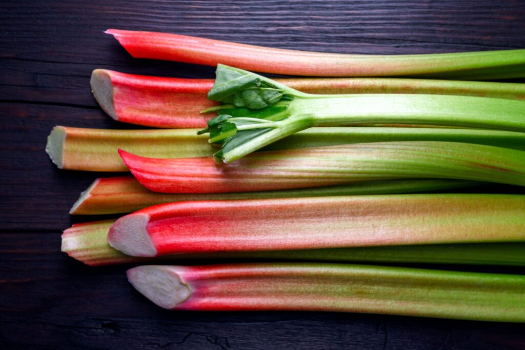 Close up of ripe rhubarb stalks on a rustic wooden table. (Smitt / Getty Images)