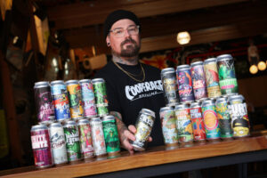 Cooperage Brewing Company art director and head of design Nicky London with the numerous beer cans featuring his artwork in Santa Rosa on Tuesday, February 3, 2026. (Christopher Chung/The Press Democrat)