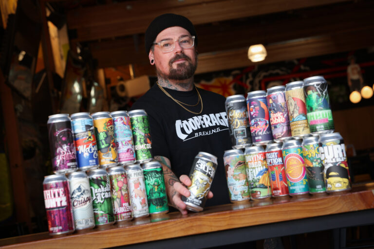 Cooperage Brewing Company art director and head of design Nicky London with the numerous beer cans featuring his artwork in Santa Rosa on Tuesday, February 3, 2026. (Christopher Chung/The Press Democrat)
