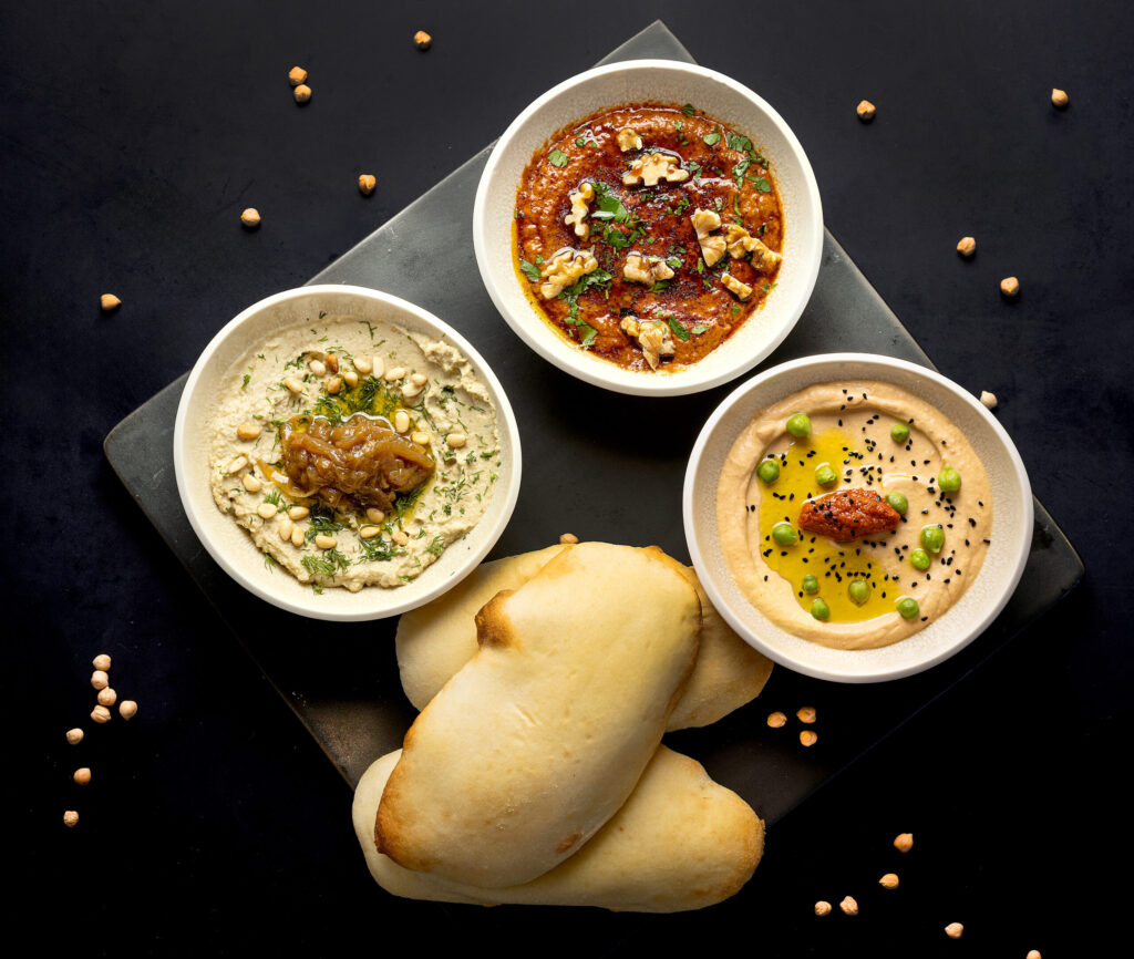 The Mezzo Trio å partager with hummus, muhammara and baba ghanoush from Juju’s, a French-Moroccan dinner pop-up in the Acorn Café space on the square in Healdsburg. Photo taken Thursday, March 19, 2026. (John Burgess/The Press Democrat)