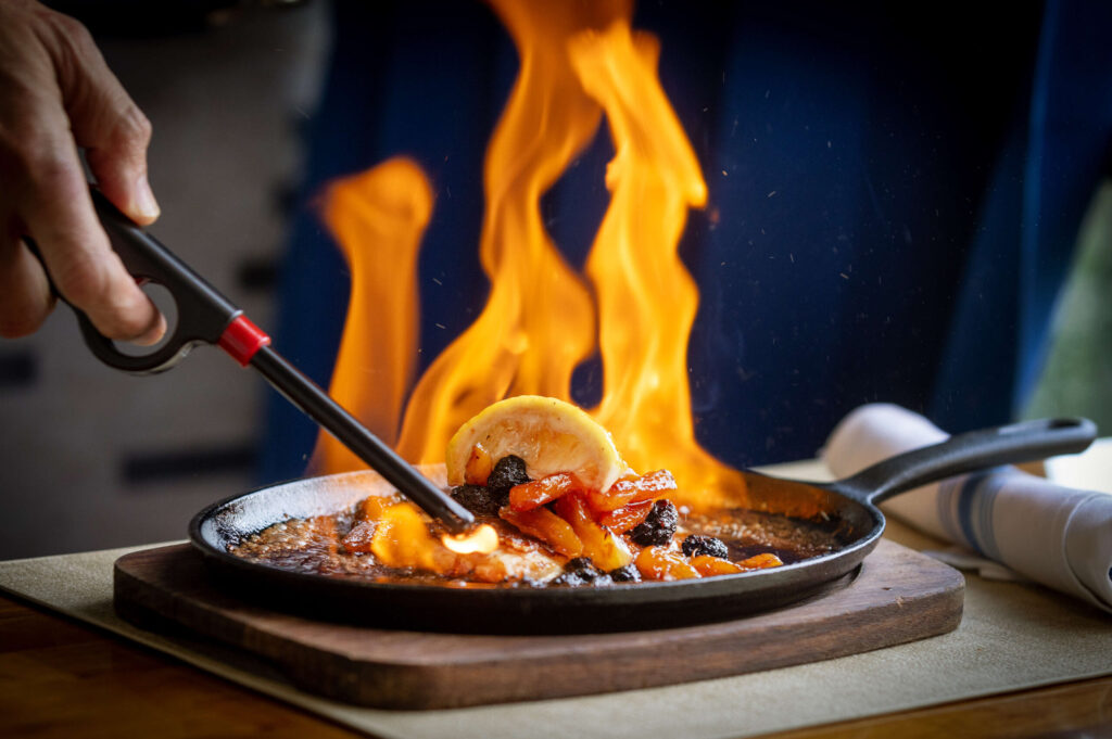 Saganaki is a spectacle for the table with a brandy flambé of Cyprus halloumi cheese, citrus honey Chardonnay raisins and Turkish apricots from Grill Santa Rosa Wednesday, December 18, 2024 at the front of the Santa Rosa Plaza. (John Burgess / The Press Democrat)