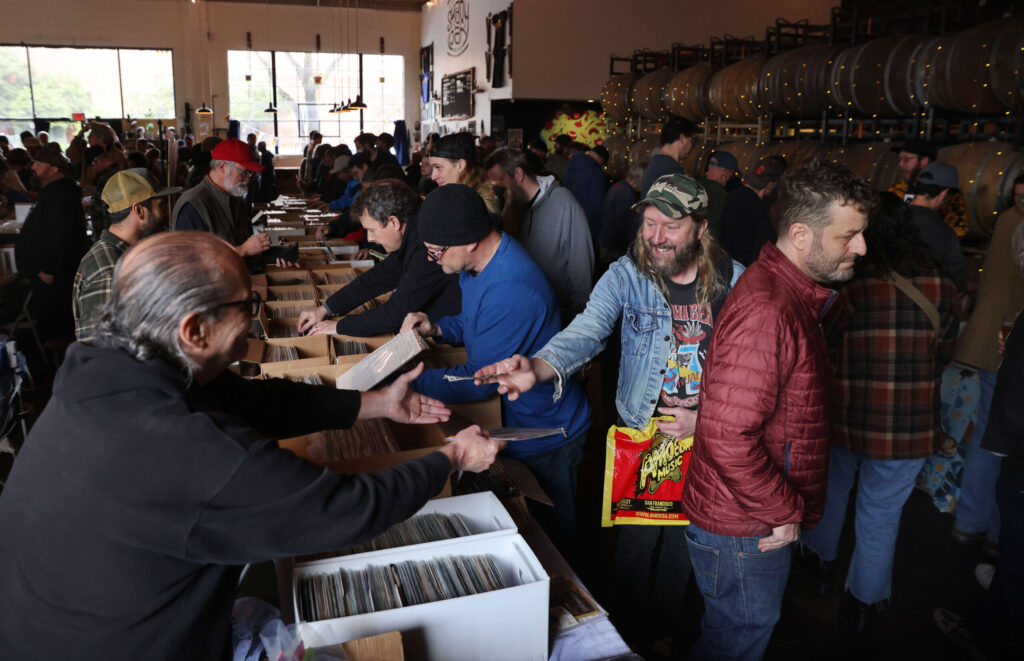 Toby Barber of Guerneville, right, gives vendor Tom Timony, left, cash for his record purchase during the Sonoma County Record Show, organized in partnership with RadioThrift and The NorCal Vinyl Society, at Shady Oak Barrel House in Santa Rosa, Sunday, March 19, 2023. (Beth Schlanker/The Press Democrat)