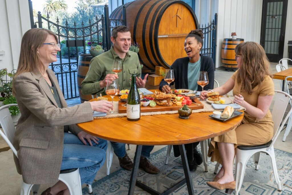 People sipping wine at Anaba Wines in Sonoma and eating from a brunch board with waffles and fruit