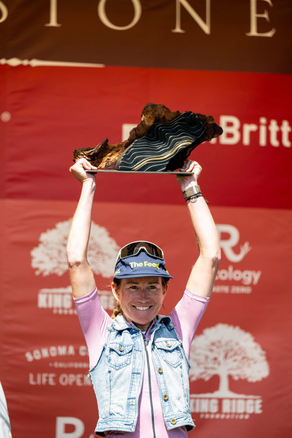 Lauren Stephens, 2025 winner in the women's division of The Growler, a race within Levi’s GranFondo, hoists the Rappensperger-designed burl and brass trophy over her head. (Jenny Keller Photography)