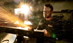 Klaus Rappensperger smooths out an edge on a custom metal project at Schnitzkraft Steel Artistry in Santa Rosa, Thursday, Jan. 29, 2026. (Kent Porter / The Press Democrat)