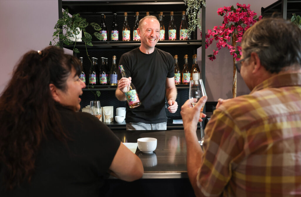 Owner Ryan Kuhlmann, center, talks with Nancy DeKubber, left, and Michael Taylor about wine at the Wolves Lovers + Thieves tasting room in Glen Ellen on Friday, March 13, 2026. (Christopher Chung/The Press Democrat)